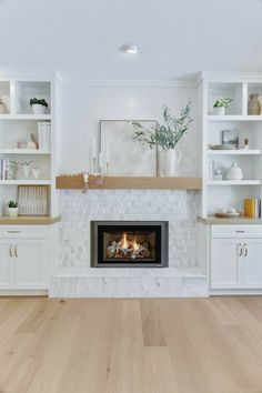 a living room with a fire place in the center and white cabinets on both sides