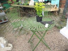 a table and chairs in a yard with plants on the ground next to each other