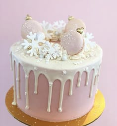 a pink cake with white icing and snowflakes on top, sitting on a gold platter