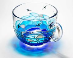 a blue glass cup with birds painted on it