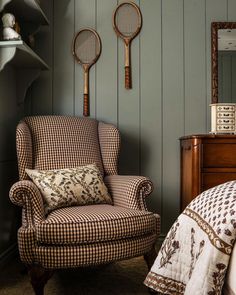 two tennis rackets hang on the wall above a chair and bed in a bedroom