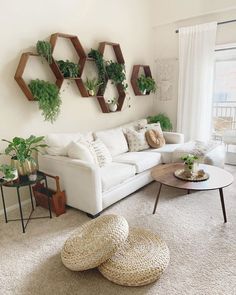 a living room filled with white furniture and lots of greenery on the wall above