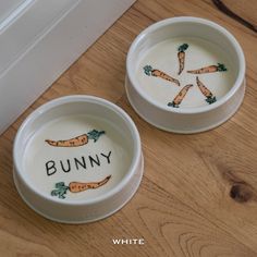 two bowls with carrots painted on them sitting on the floor next to each other