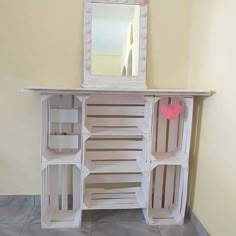 a white wooden cabinet sitting on top of a tiled floor next to a wall with a mirror above it