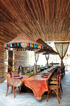 an outdoor dining area with wooden tables and umbrellas hanging from the rafter ceiling