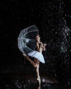 a young ballerina is dancing in the rain with an umbrella and some water droplets