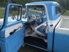 the interior of an old blue and white truck with its door open to show it's dashboard