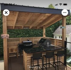 an outdoor kitchen with bar stools and grill