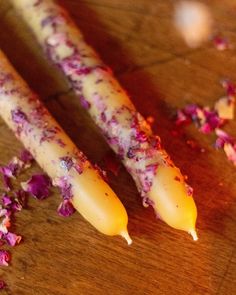 two purple carrots on a wooden cutting board