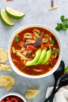 a bowl of chicken tortilla soup with avocado and cilantro