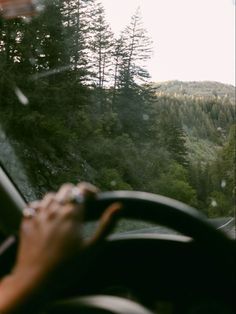 a person driving a car on a road with trees in the background