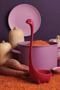 a pink flamingo standing next to purple bowls and vegetables