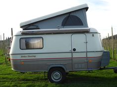 an rv is parked in the grass near some vines