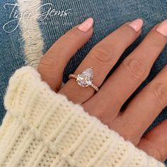 a woman's hand wearing a ring with a diamond on the band and a white sweater