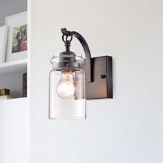 a light fixture mounted on the side of a wall with a glass jar hanging from it