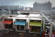 an aerial view of several buildings with colorful awnings on them and a ferris wheel in the background