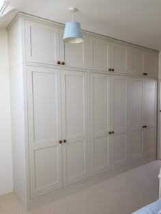 an empty bedroom with white cupboards and a blue lamp hanging from the ceiling above