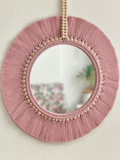 a round mirror hanging on the wall with beaded trimmings and beads around it