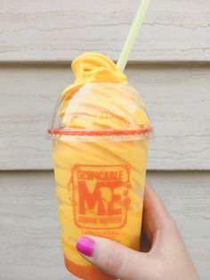 a person holding up a yellow drink in their hand