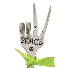 a pair of scissors with the words peace on them tied to each other in a green ribbon