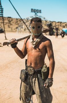 a man wearing a mask and holding a baseball bat in his hand while standing on a dirt road