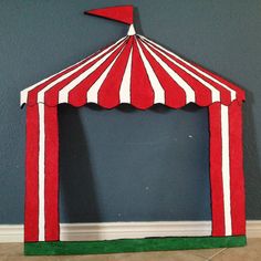 a red and white striped tent sitting on top of a floor next to a wall