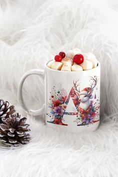 a mug with marshmallows in it and a pine cone