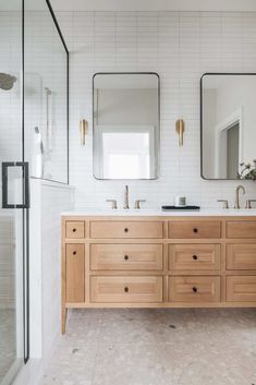 a bathroom with two sinks and mirrors on the wall next to a walk in shower