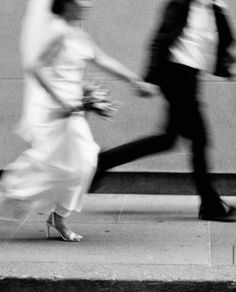 black and white photograph of two people walking down the street, one holding hands with the other