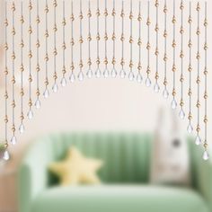 a living room with a green couch and gold beads hanging from the ceiling