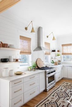 a kitchen with white cabinets and an oven in the center, surrounded by wooden flooring