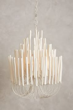 a white chandelier hanging from a chain with sticks sticking out of the bottom