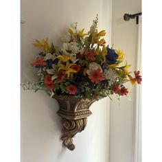 a wall mounted vase filled with lots of colorful flowers on top of a white wall