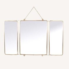 three mirrors hanging from a chain on a white wall with one mirror in the middle