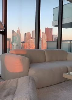 a white couch sitting in front of a window next to a table with a lamp on it