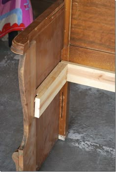 a close up of a wooden bed headboard and foot board on concrete flooring