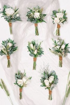 wedding bouquets laid out on a white sheet with greenery and flowers in them