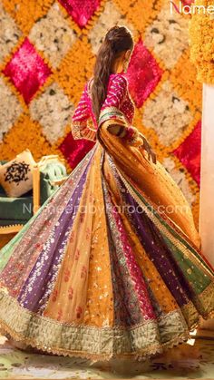 a woman standing in front of a quilted wall wearing a colorful dress and veil