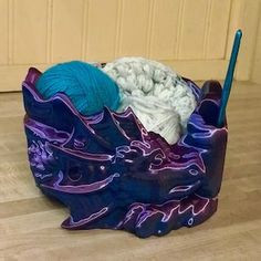 a blue and purple container with yarn in it on the floor next to a door