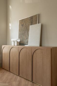 a wooden cabinet sitting in the middle of a room next to a painting on a wall