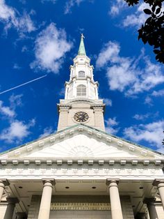 a tall white building with a clock on it's side and columns in front