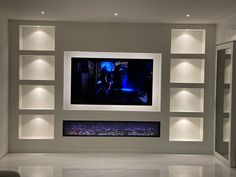 a large television mounted to the side of a wall in a living room with built - in shelving