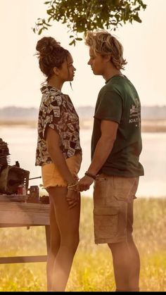 a man and woman standing next to each other in front of a table with an old camera on it