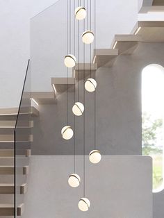 the light fixture is hanging from the ceiling above the stairs in this modern house with white walls and concrete flooring