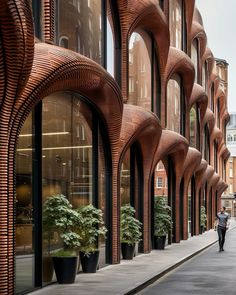 a man walking down a street next to tall buildings with arches on the front and sides