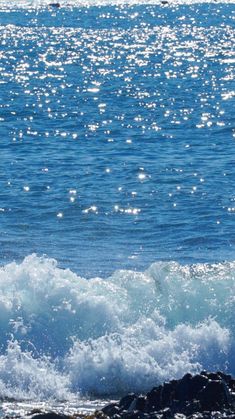 a man riding a wave on top of a surfboard in the ocean next to rocks