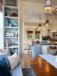 an open kitchen and dining room area with bookshelves on the wall, blue striped chairs