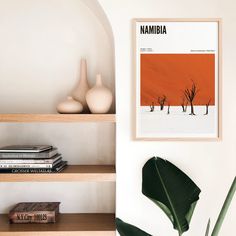 a shelf with books and vases on top of it next to a wall mounted poster