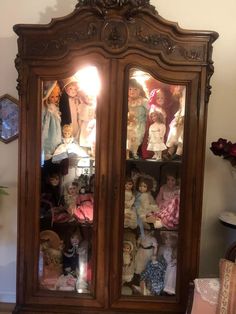 an antique china cabinet with many dolls in it