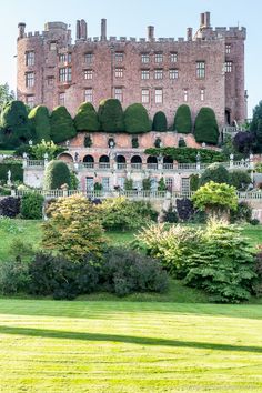 an old castle with trees and bushes surrounding it